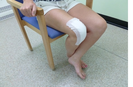 A patient in a chair has their legs crossed at the shins.