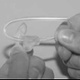 Image shows a close up of two hands pushing the new tube through the ear-mould.