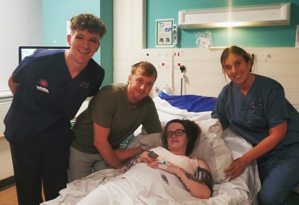 Image of a woman in a hospital bed, with her partner and two midwives.