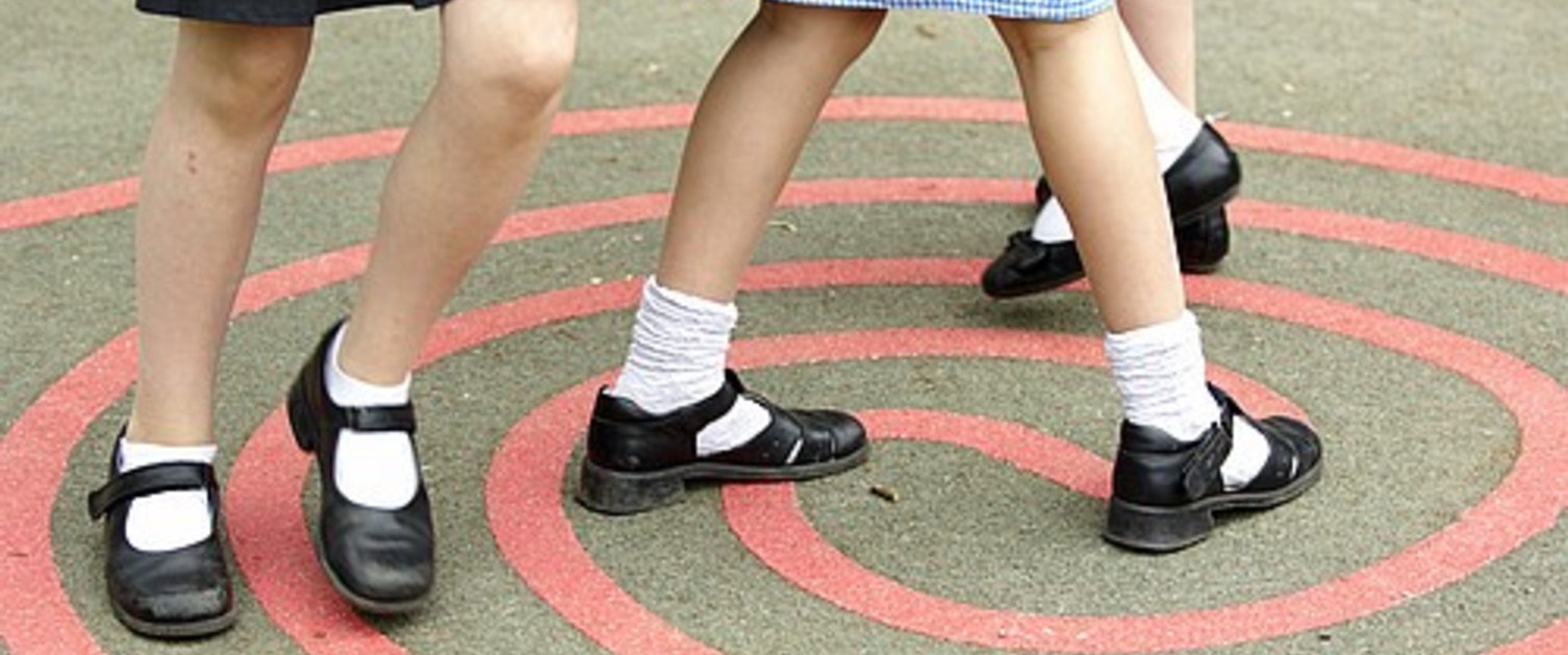 A image of girls legs as they walk through a play ground