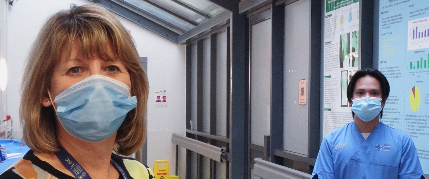 Two people wearing face masks inside a hospital corridor