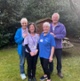 Image shows three women and a man standing in a garden