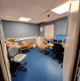 Image shows small office with the Audiologists desk in the corner and a wooden patient’s chair beside it.
