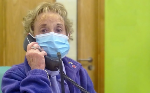 Image shows volunteer wearing face mask talking on a telephone
