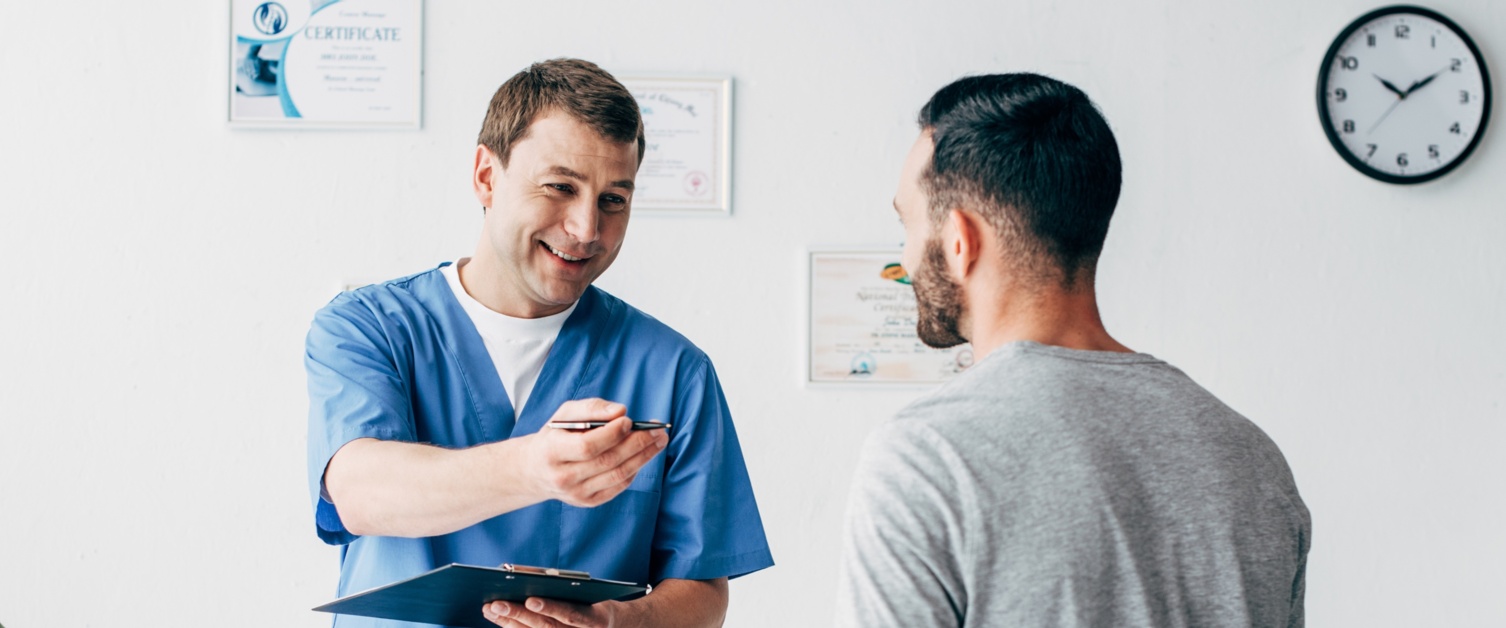 A male nurse talks to a male patient.