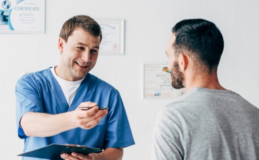 A male nurse talks to a male patient.