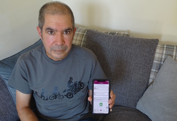 Image shows a man holding a mobile phone.