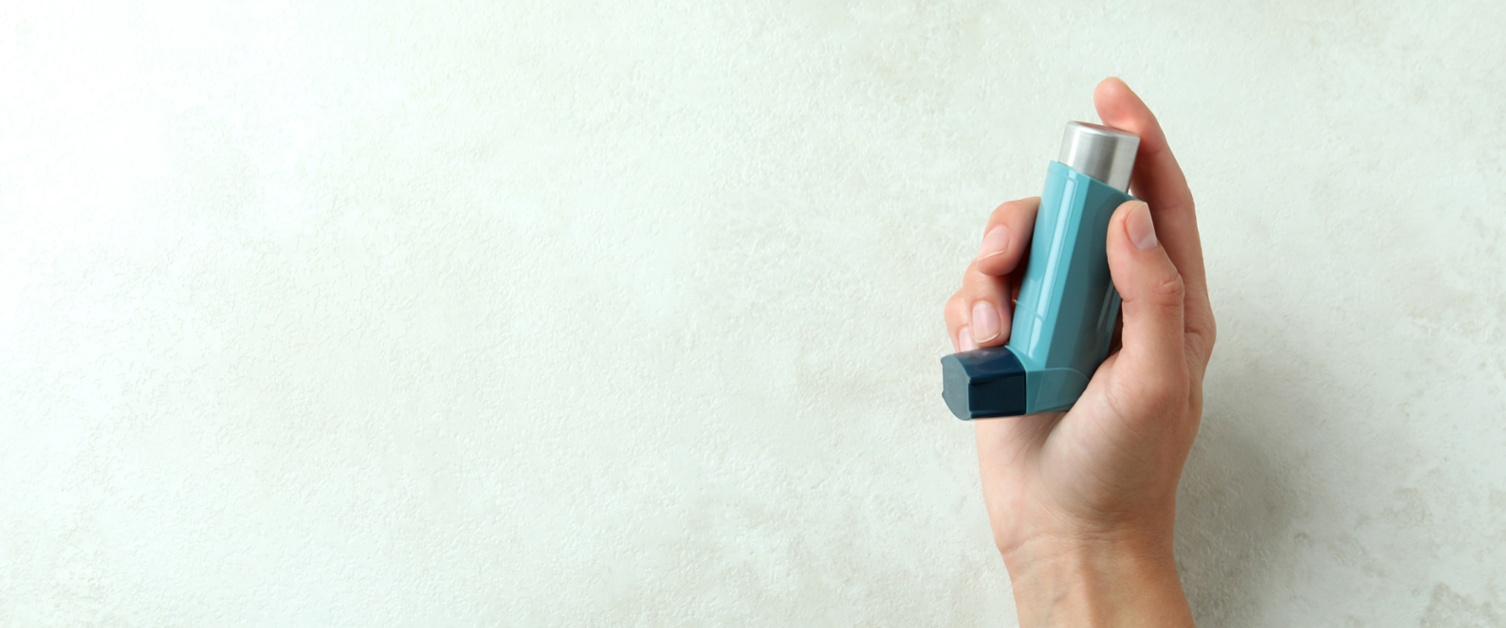 Image shows a hand holding an inhaler
