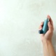 Image shows a hand holding an inhaler