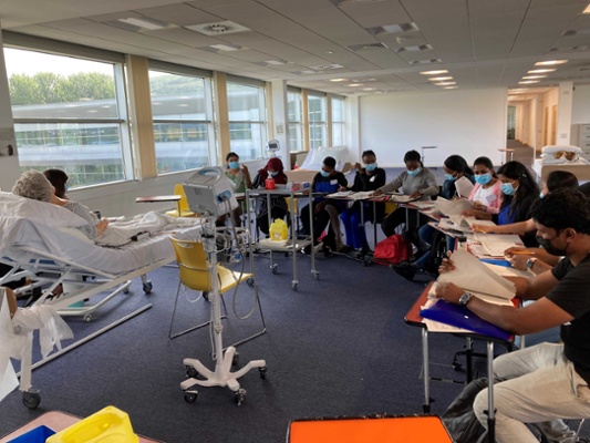 Image shows a group of people sitting at desks