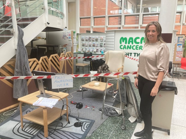 A woman standing next to a demonstration of an untidy living room