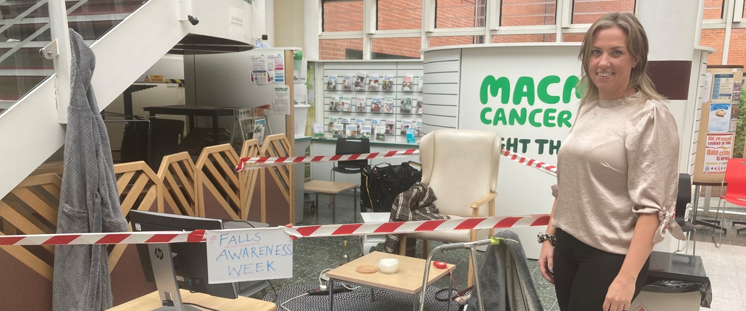 A woman standing next to a demonstration of an untidy living room