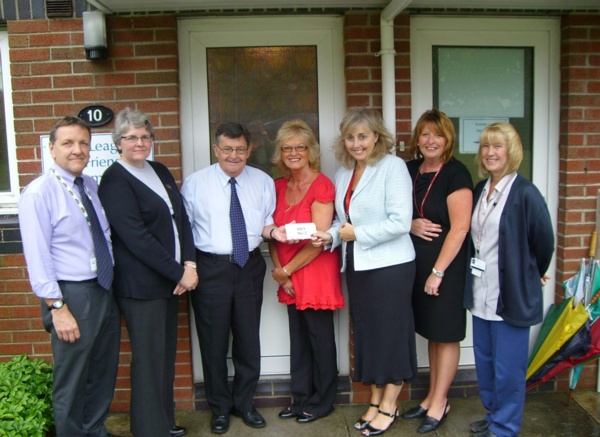 Image shows a group of seven people outside the front door of the new family accommodation.