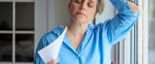 A woman cooling herself with a piece of paper