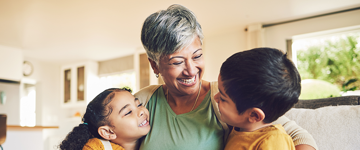 Image shows a woman sat on a sofa with her arms around a child on either side.