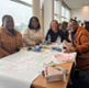 Image shows a group of people sat around a table