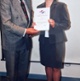 Image shows a woman being presented with a certificate by a man