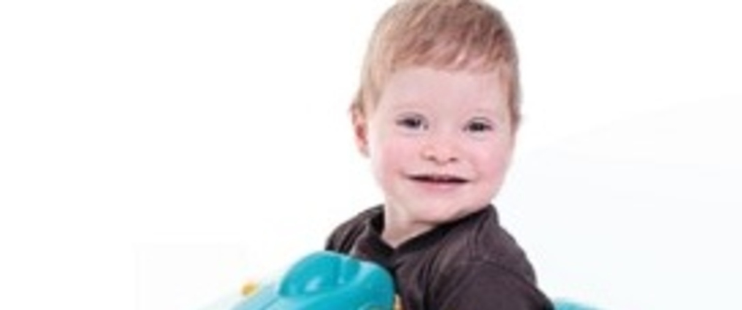 A young boy playing on a toy seesaw