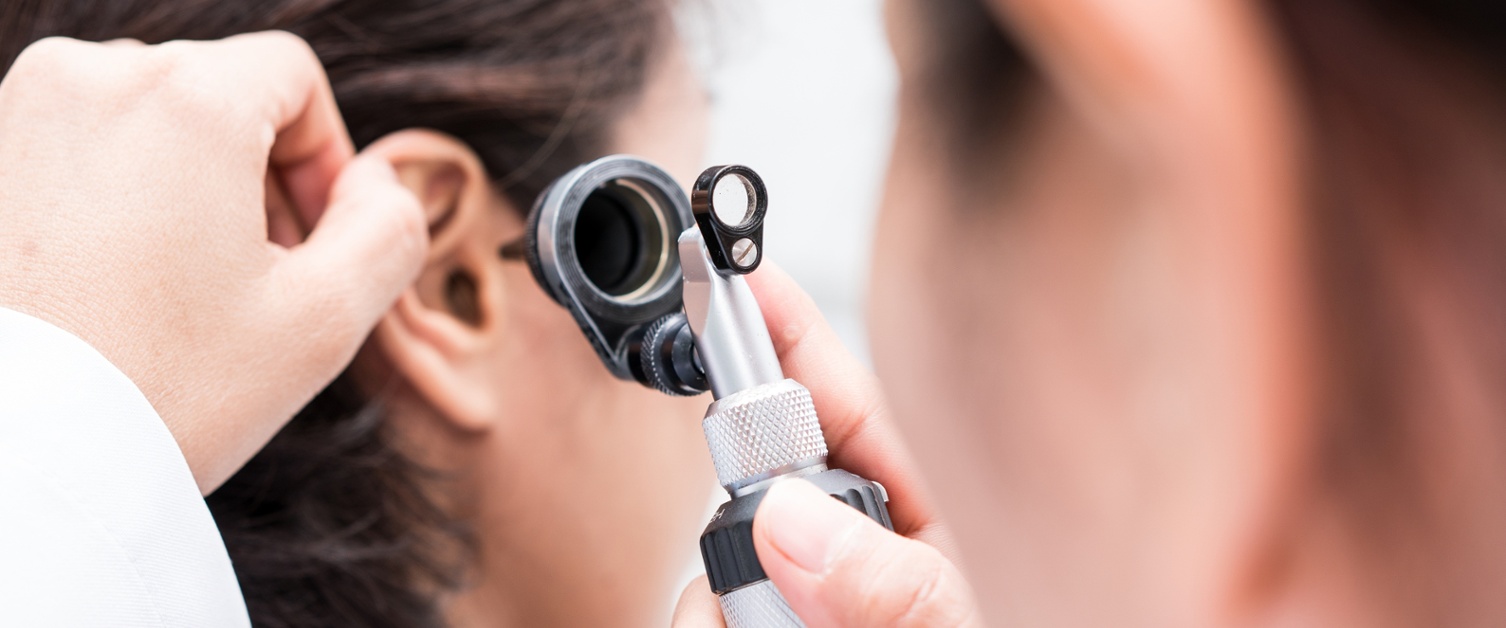 Image shows Audiologist examining a patient’s ear.