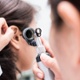 Image shows Audiologist examining a patients ear.