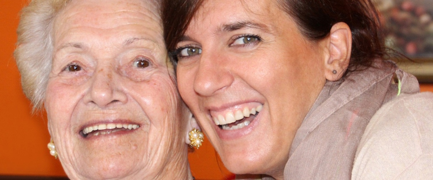 Older and younger woman smiling together.