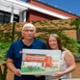 Two people hold a painting of Morriston Hospital.