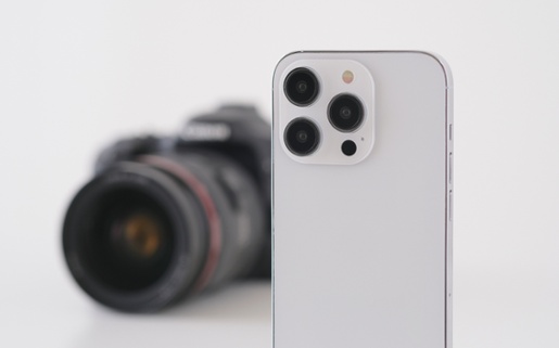 An image of a silver phone, with a camera blurred in the background to represent photography.