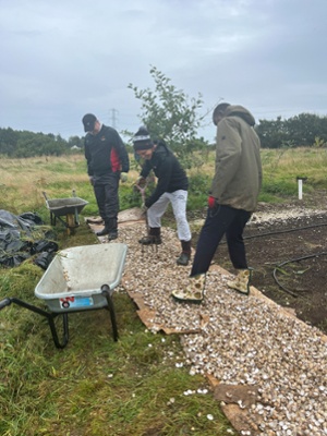 Image shows men raking stones