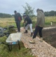 Image shows men raking stones