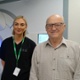 A smiling man, with a nurse standing just behind him in a hospital treatment room