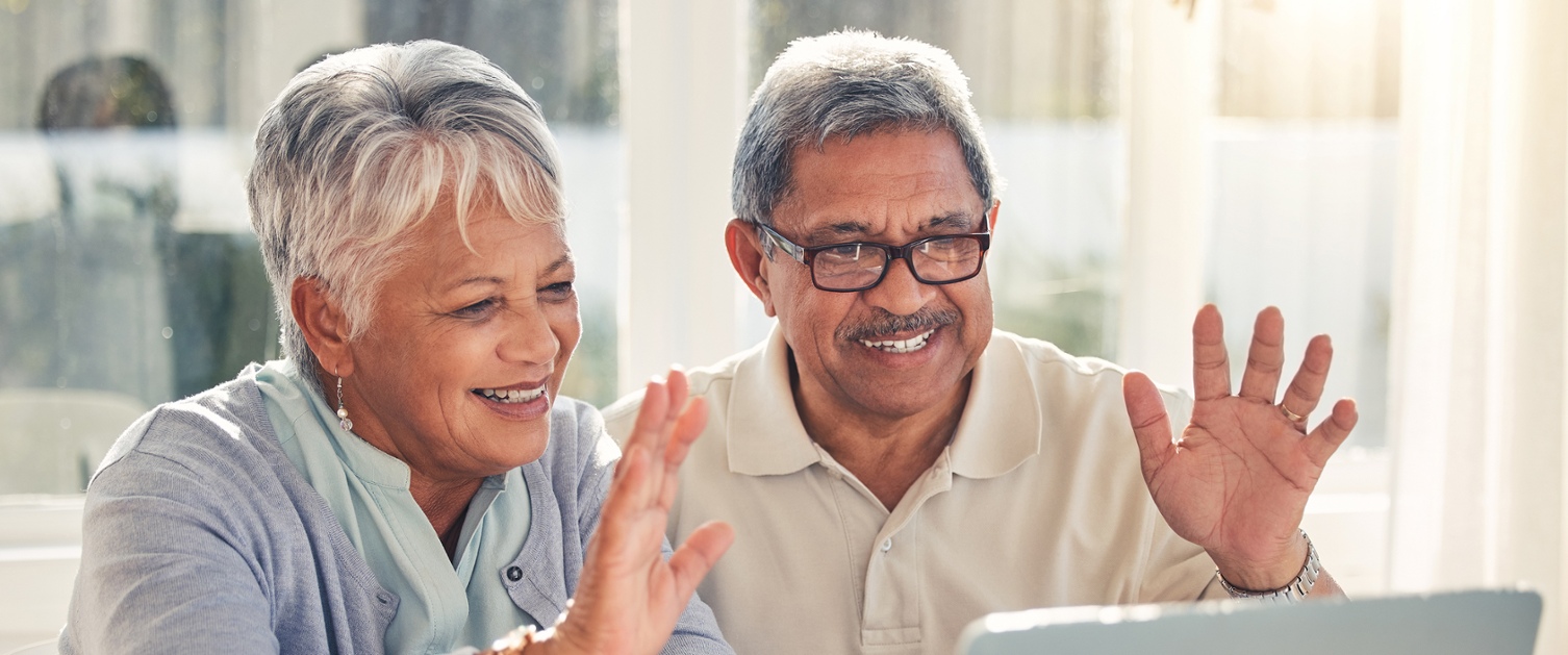 Older couple on a video call on a laptop are waving.