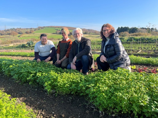 Image shows four people crouching behind some crops