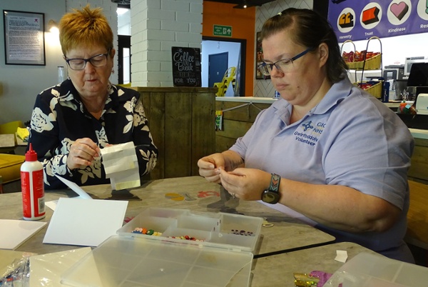 Image shows two people doing arts and crafts in a cafe.