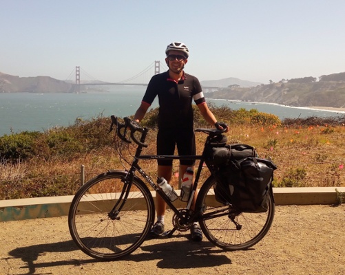 Image shows a man stood behind a bike