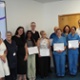 A group of smiling hospital staff holding certificates