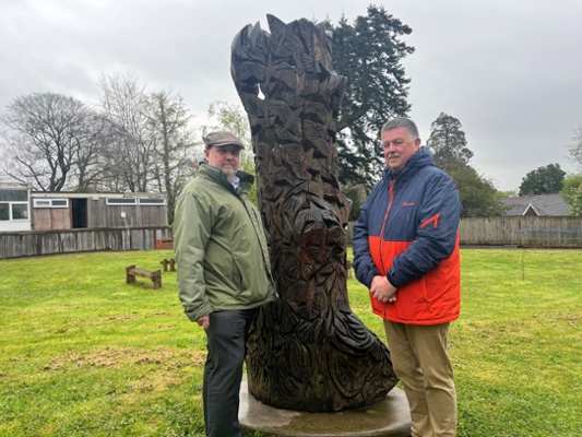 Image shows two men in front of a tree