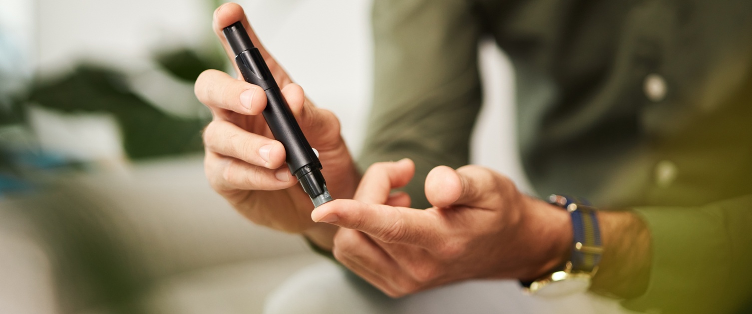 A man takes a finger prick test with a blood glucose monitor.