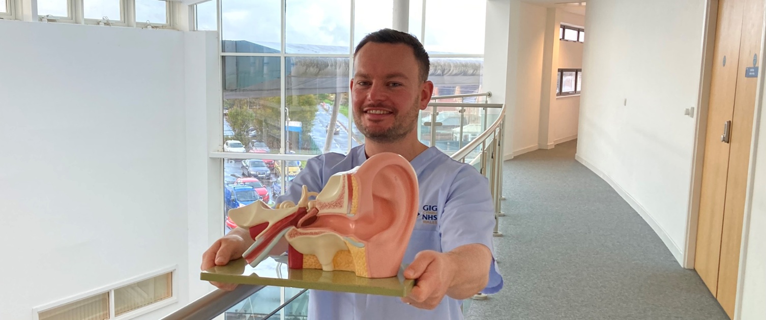 A man holding a plastic model of an ear