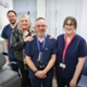 Image shows three clinicians and a patient in a hospital room.