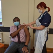 CEO of the CAE Franck Banza is pictured receiving an injection of COVID-19 vaccine from GP practice nurse Heather Featon.