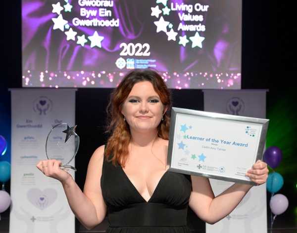 Image shows a young woman with awards at an award ceremony