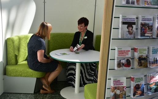 Two women talk at a table in a Macmillan Information Pod