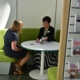 Two women talk at a table in a Macmillan Information Pod