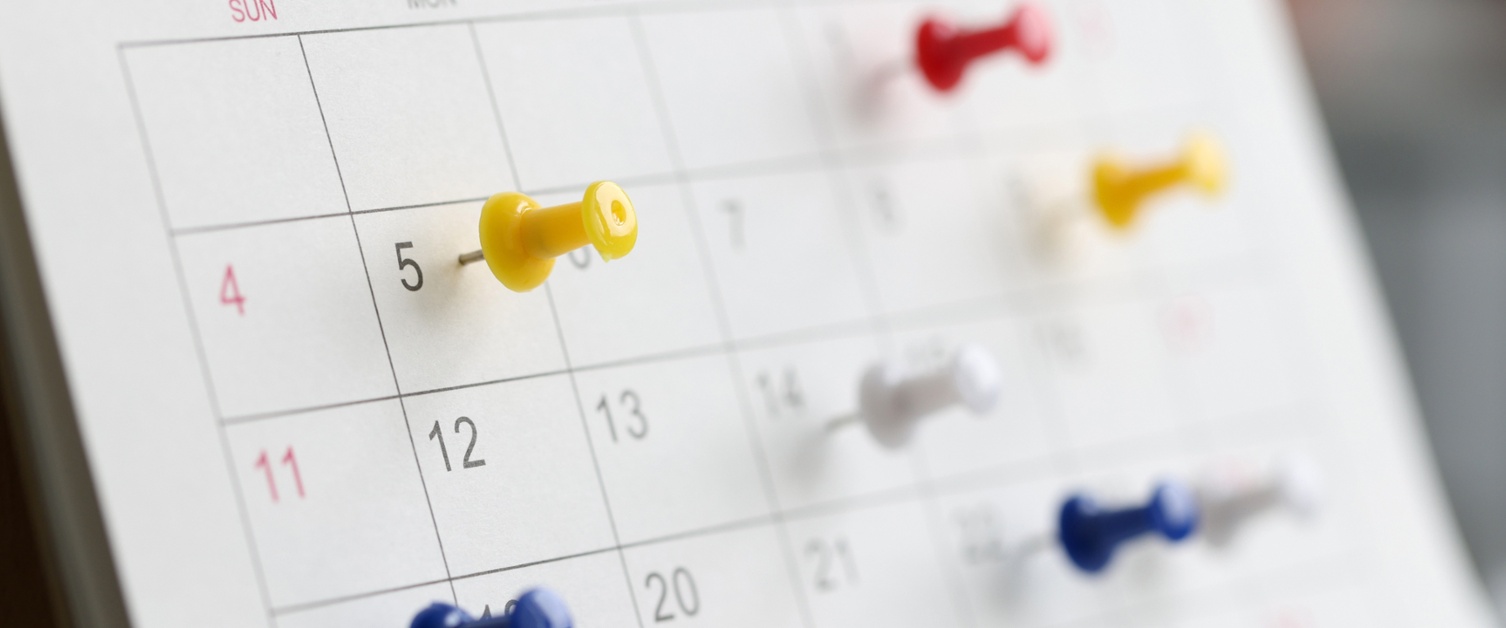 Pins in date boxes on a white calendar
