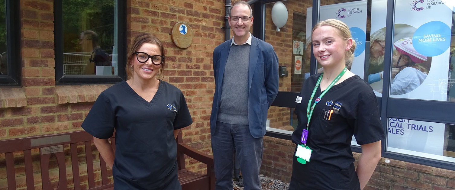 Image shows three people standing outside a hospital building.