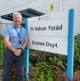 Image shows a man standing next to a white sign