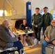 Image shows a group of people standing around a woman in a hospital bed