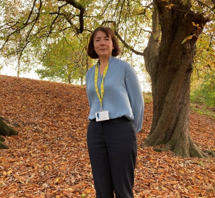 Image shows a woman standing in a park