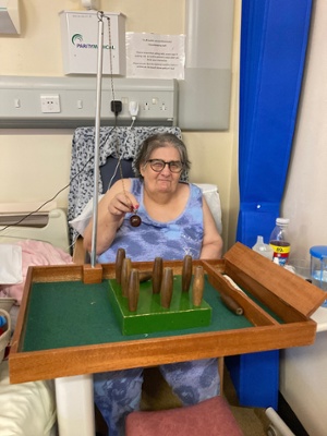 Image shows a woman sitting on a chair while playing table skittles