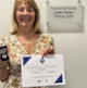 Image shows a woman holding a certificate